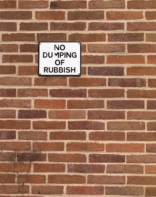 A rectangular black-and-white metal sign mounted on a red brick wall displaying the message 